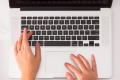A womans hands typing on a Mac keyboard