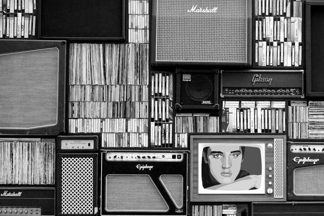 Black and white photo of a wall of antiquated media and amplifiers. 