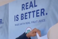 A hand is tearing off a poster that says "REAL IS BETTER."